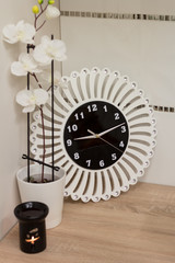  Black clock with white and shiny decorations standing on the counter surrounded by decorative items