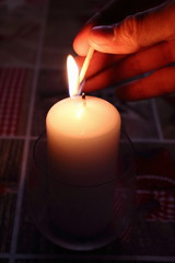 Hand lighting candle with burning flame. Spiritual religious background. Sorrow and pray concept. Christmas holiday decoration. Romantic love valentine's day mood. 