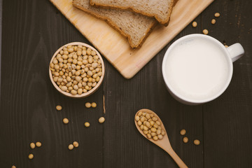 Glass with soy milk and soy bean on wooden background