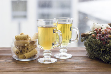 Happy New Year's morning with glass tea cups, a bowl of cookies and a pine wreath,light background