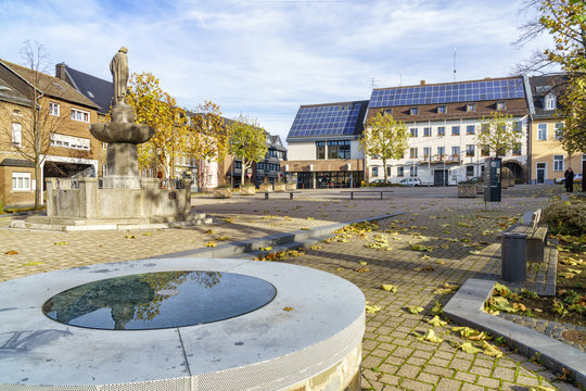Marktplatz vor neuem Zülpicher Rathaus mit Kriegerdenkmal (fälschlich Chlodwigdenkmal) und abgedecktem mittelalterlichen Brunnen im Vordergrund. Im Boden ist ein großes mittelalterliches Gräberfeld 
