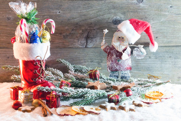 Gefüllter Nikolausstiefel und Nikolaus mit Mütze rustikal vor Holzhintergrund