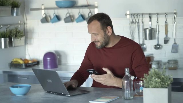 Busy man multitasking, with tablet, laptop and smartphone by table at home
