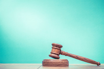 Retro auction or judge wooden gavel on table front mint green background. Vintage old style...