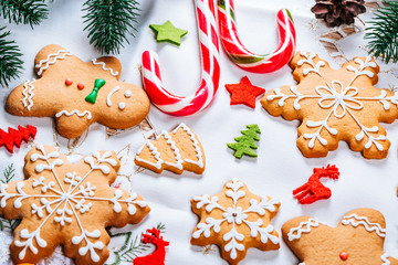 Christmas gingerbread cookies homemade with branches of Christmas tree and New Year decor on table with white tablecloth. Merry Christmas postcard