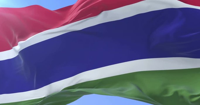Gambian flag waving at wind in slow in blue sky, loop