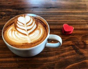 Cup of love , heart latte art coffee in white cup and red love heart on the vintage wooden table. Love coffee love in your cup. Wake up and full fill energy, top view.