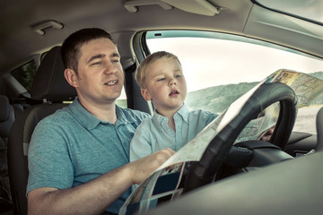 Father and son looking on map in car