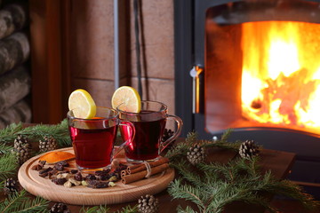 Mulled wine. A couple of mugs of mulled wine on a wooden table among the fir branches in front of the fireplace.