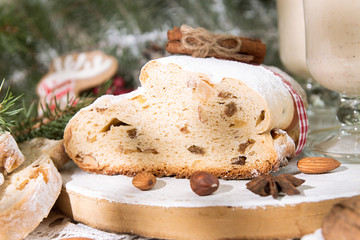 Traditional Christmas dresden cake stollen with candied fruits and almonds, glasses eggnog. Christmas New Year decoration.