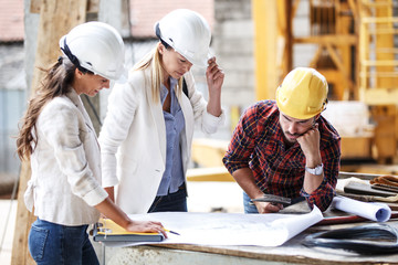 Two female inspectors and architects discuss with head engineer about construction project.People...