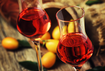 Kumquat liqueur, vintage wood background, selective focus