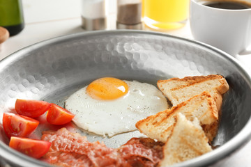 Frying pan with egg, bacon, toasts and tomatoes, closeup