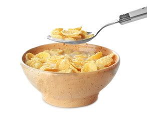 Bowl and spoon with corn flakes and milk on white background