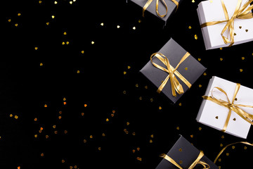 Black and white gift boxes with gold ribbon on shine background. Flat lay. Copy space.