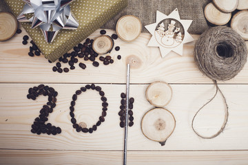 2018 inscription of coffee beans, golden gift box with a silver bow on a light wooden background, top view