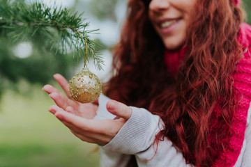 Crop woman decorating tree with christmas balls