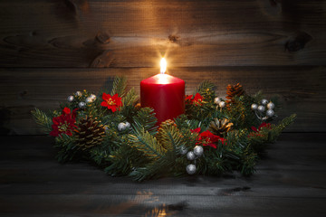 First Advent - Decorated Advent wreath with a red burning candle on a wooden background with...