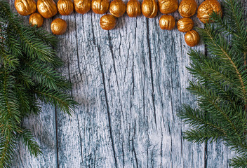 Branches of fir trees with Christmas ornaments of gilded nuts on a background of old wooden panels, Christmas background