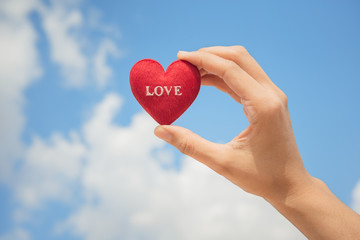 Obraz premium Hand hold red heart with blue sky background for valentine concept