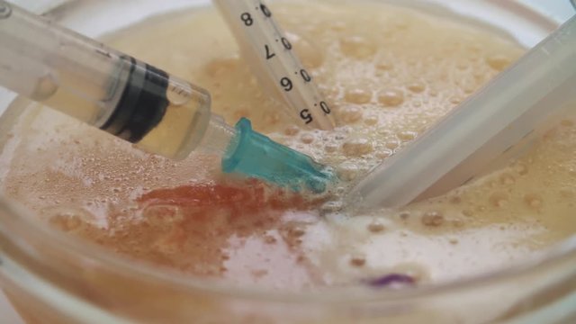 Medical syringe put in a glass bowl with drugs stands on the table 
