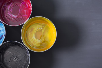 Top view of old CMYK paint cans on dark background. Colorful background.