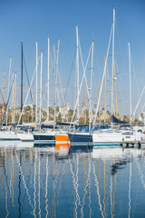 Horizontal photo of luxury and glamorous yachts and sailboats docked or parked in marina port in barcelona, spain, for winter vacation