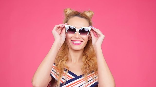 Young woman on a pink background with sunglasses
