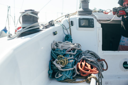 Nautical ropes, buntine, capstan and cablet piled up on deck of professional racing yacht or sailboat, attached to mast or forestay, different colors, expensive sailing hobby