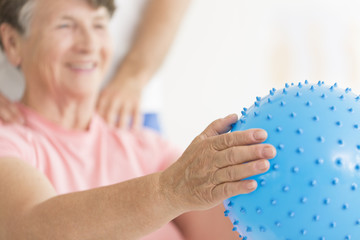 Elderly woman holding blue ball