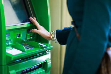 Photo of woman with clock on hand at green cash machine