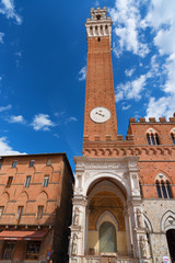 Fototapeta premium Detail of the Torre del Mangia 87 m. (Tower of Mangia) on blue sky with clouds. Siena, Italy