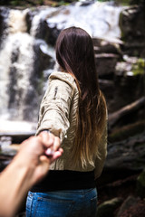 The girl leads her boyfriend to a beautiful waterfall. Nature