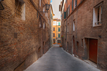 Fototapeta na wymiar Beautiful medieval narrow street in the spring, Siena, Italy. Historic centre of Siena has been declared by UNESCO a World Heritage Site.