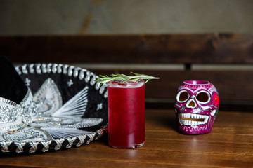A horizontal image of a red cocktail with ice cubes in a highball glass, decorated with rosemary....