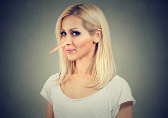 Smiling cunning woman with long nose isolated on gray background. Liar concept. Face expressions,...