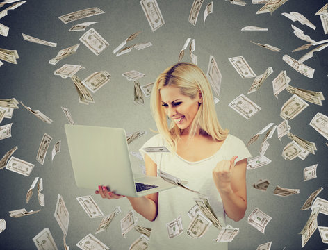 Successful woman using laptop building online business making money dollar bills cash falling down. Beginner IT entrepreneur success economy concept
