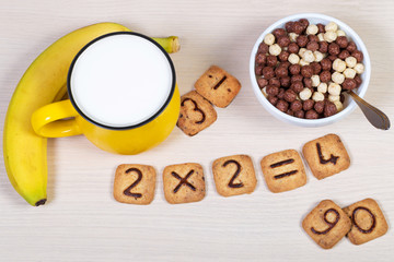 Healthy breakfast for a child or pupil. Chololate cereals, milk, banana and funny cookies with...