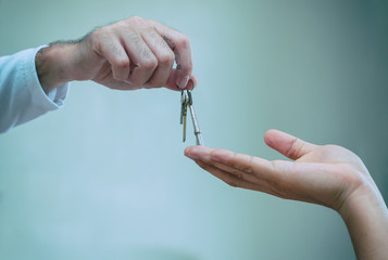 Close up of realtor hand giving house key to owner home, buying selling property business.