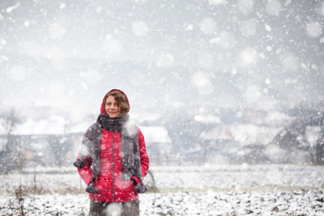 Fototapeta na wymiar woman in red coat walking in heavy snowfall in the countryside