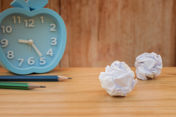 Business Creative and Idea Concept, Time Management Concept : Used  two pencil with many white crumpled paper ball and alarm clock put on wooden floor. (Selective focus)