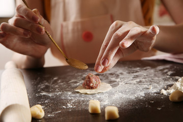 Process of making ravioli, pelmeni or dumplings with meat on wooden table