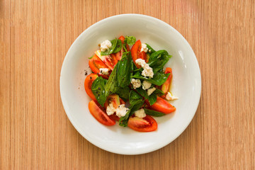 Salad with leaves, tomato and cheese. Overhead view. Selective focus.