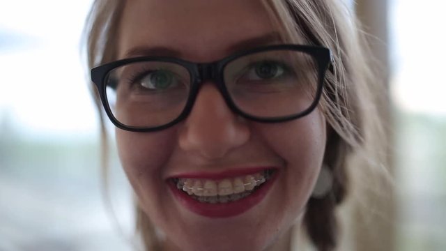 Young girl in glasses with braces smiling and laughing looking at camera.