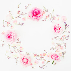Floral round frame of pink roses, wild flowers and petals on white background. Flat lay, Top view.