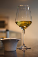 Glass of white wine on bar with small bowl of tapas