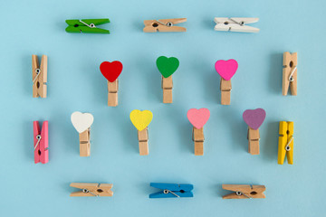 Frame from wooden colorful pins with hearts on the blue background, top view. Decorations for...