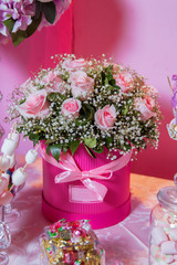 Candy Bar. Bright white interior with lots of pink flowers. Pink powder. Bouquet of delicate pink flowers in round boxes. Stairs and chair on the white with lots of bouquets of pink flowers.