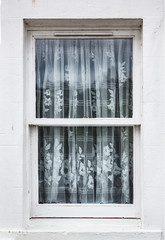 cortina de encaje transparenten motivos de flores en una ventana con marco de madera blanco y en una pared pintada de blanco