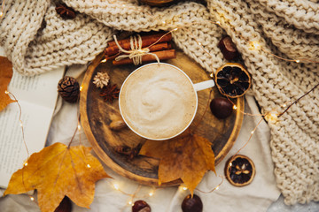 Autumn or Fall morning coffee concept. Flat lay of knitted sweater, wooden tray, mug of coffee and yellow fallen leaves. Top view,  cozy wide composition